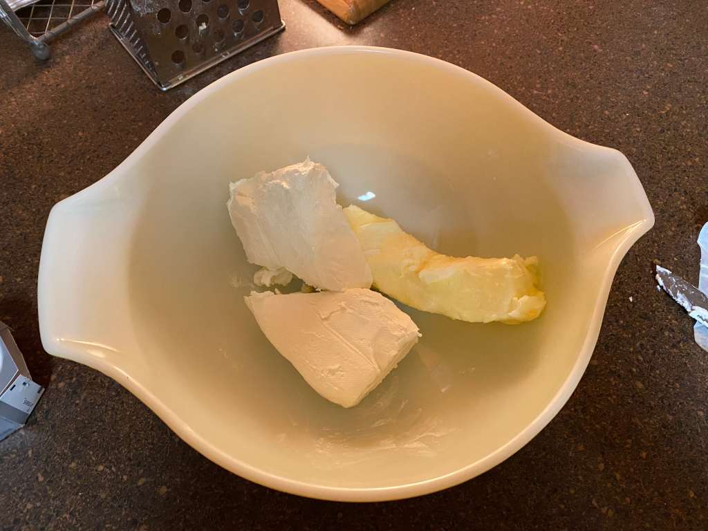 A stick of softened butter and cream cheese in a medium-sized bowl. 