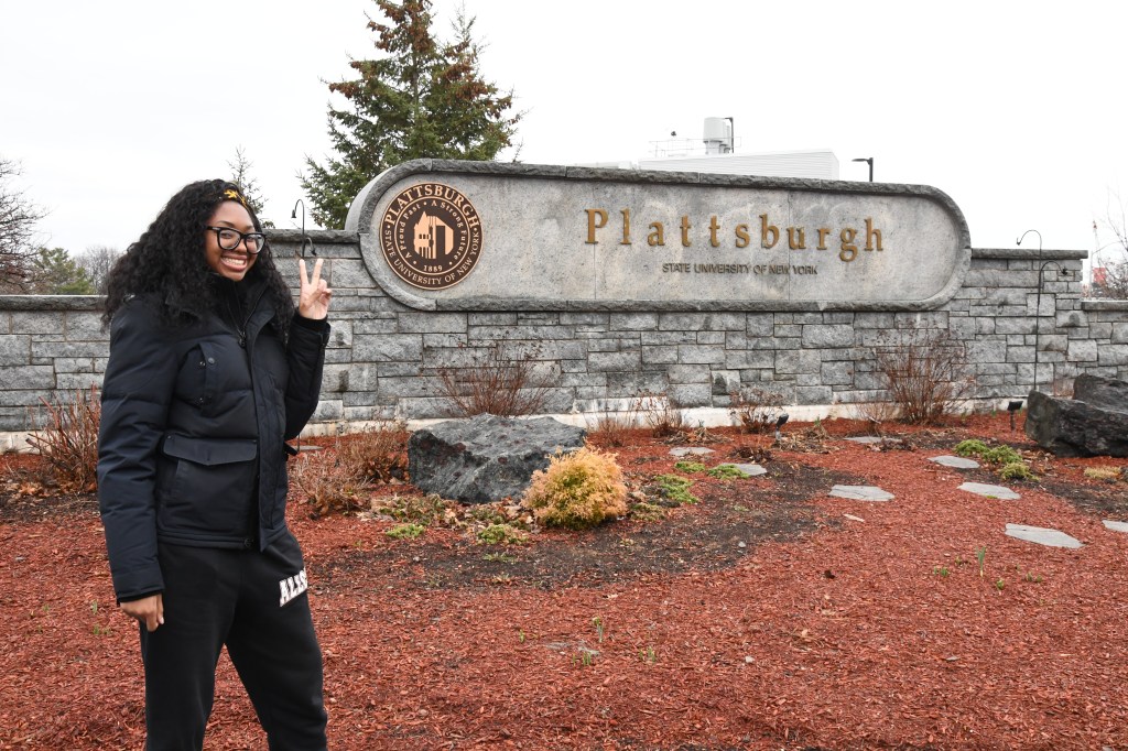 Khaelle standing in front of the SUNY Plattsburgh sign.